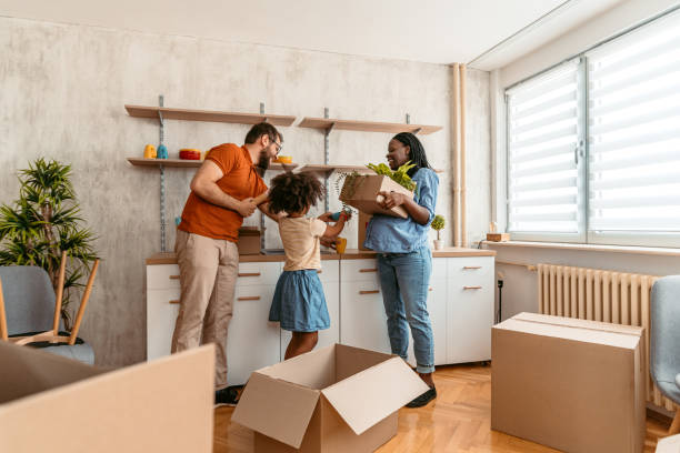 Pregnant woman with her husband and their child unpacking in their new apartment. Carrying boxes.